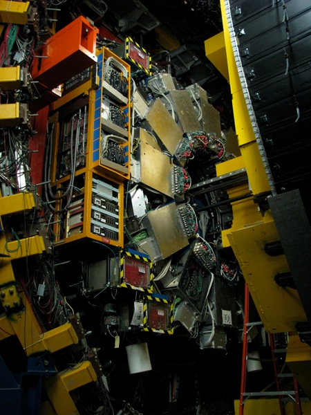 A peek inside CDF, which has been partly opened. The scale is hard to grasp here, but the ladder at the lower right corner might help. Much of what you can see is detector arrays of various sorts, along with the electronics that manage them. [Credit: moi]