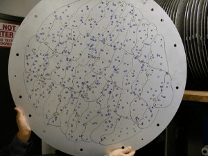 One of the aluminum plates used in the BOSS survey. Each hole in the plate corresponds to the position of a galaxy. Light from that galaxy then passes through the hole into a fiber optic cable, where its spectrum can be analyzed. The plate blocks out light from everything else, keeping the signal as clean as possible. [Credit: moi]